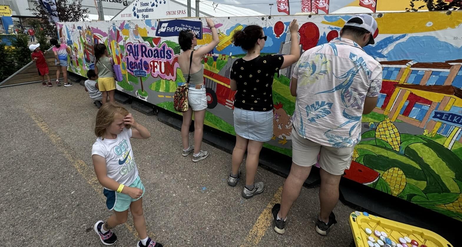 Event mural setup showing panels and participants painting
